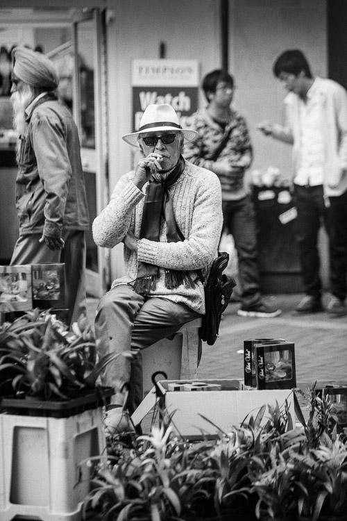 Urban life cultural diversity -an old guy selling flowers Birmingham, Sigh passer by and two Chinese guys behind