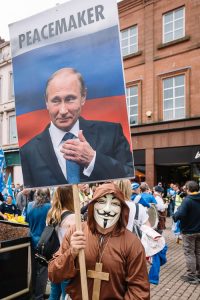 The Anonymous member with "Putin the Peacemaker" sign in All Under One Banner march