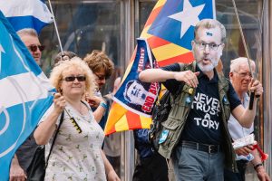 A marcher wearing "Never trust a Tory" T-shirt and a mask of David Mundell, Secretary of State for Scotland, with a Yes meme on the forehead