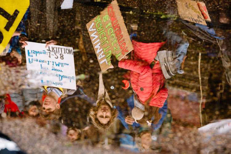 Climate emergency protesters reflected in a puddle at Blue Wave 2020