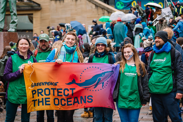 Greenpeace activists posing with the sign "Protect the Oceans"