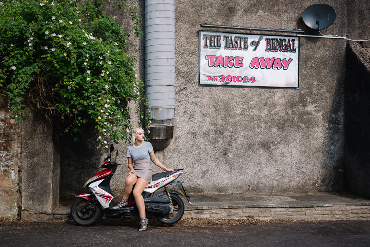Vintage urban shoot - Emily on a scooter parked near a dog rose bush