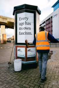 "Every age has its fascism" poster being applied